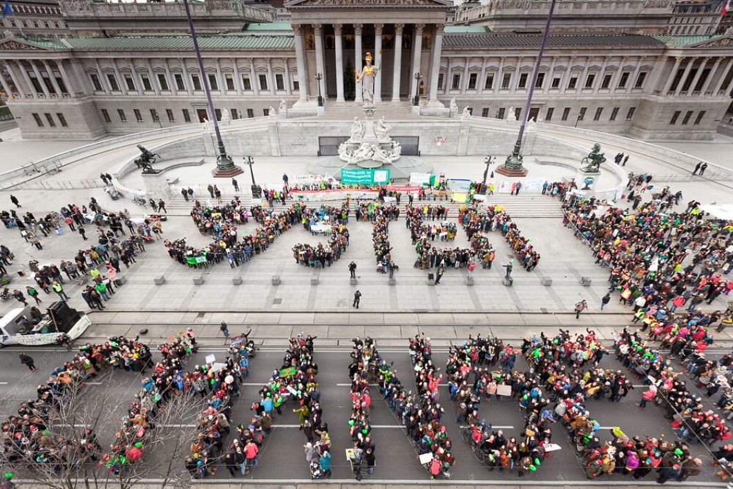 Activists spelling out systems change in front of a building