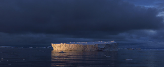 Iceberg in the ocean at sunset